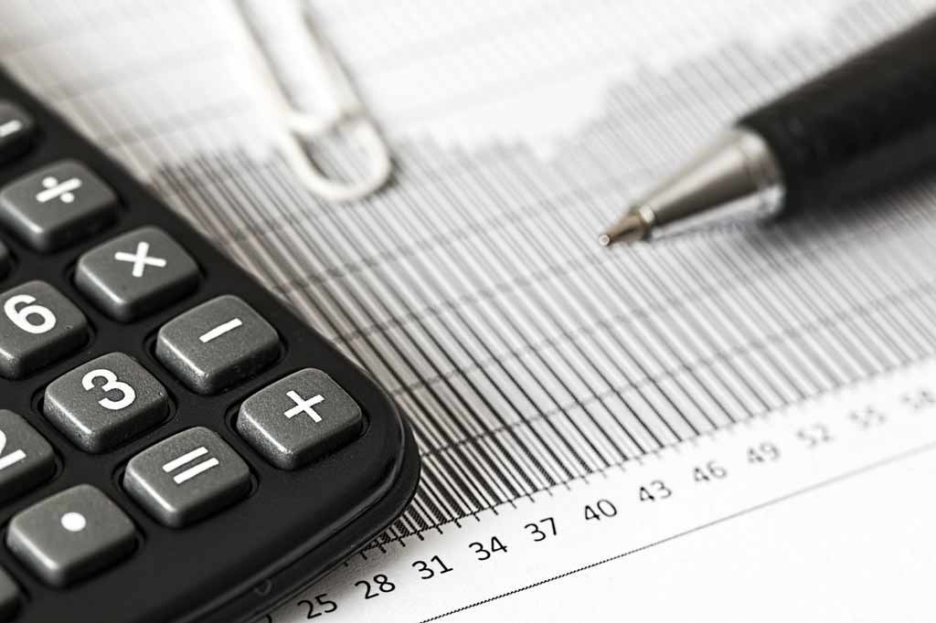 A Calculator, a Pen and a book on a table