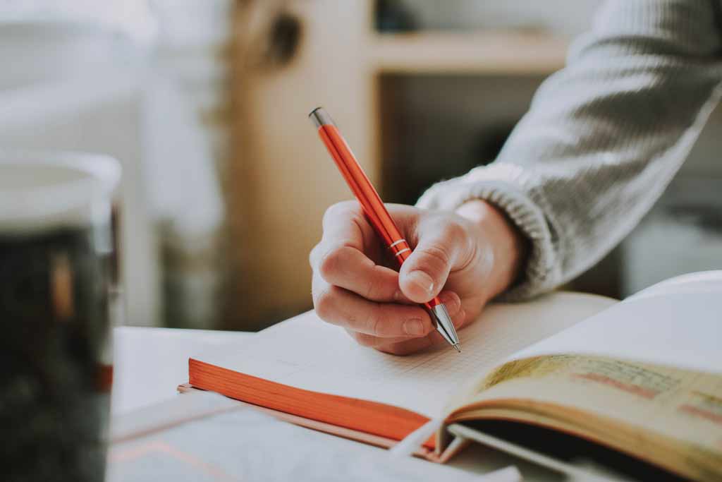 Hand writing on a book with a pencil