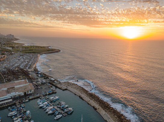 Aerial view of the Tel Aviv coastline with boats and a dock in Israel